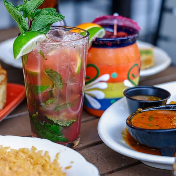 A refreshing red cocktail with lime and mint, alongside a colorful drink and Mexican food.