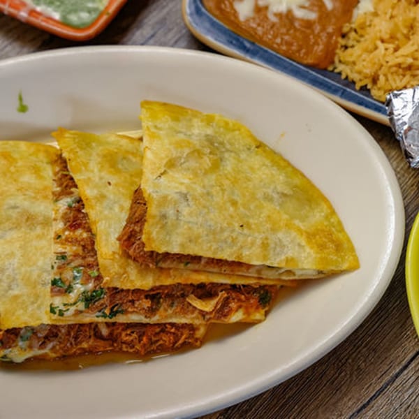 Golden-brown quesadillas filled with meat and cheese, served on a white oval plate.